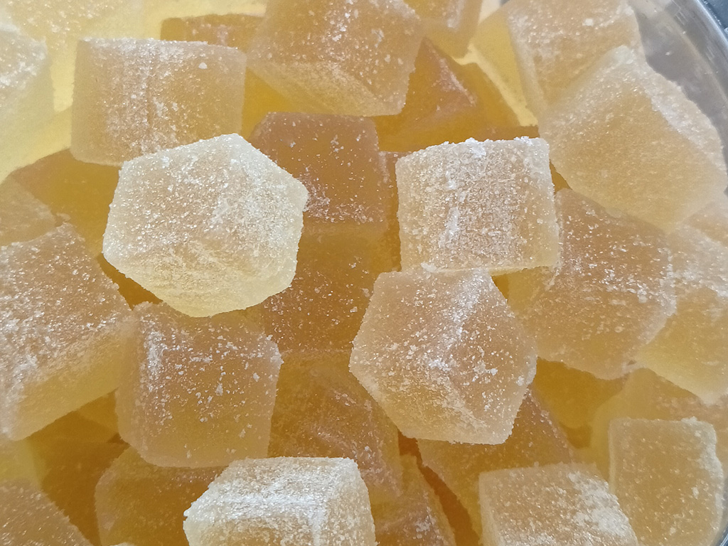 Handgjord ananasmarmelad, ljust gul, skuren i kuber och rullade i fint strösocker.